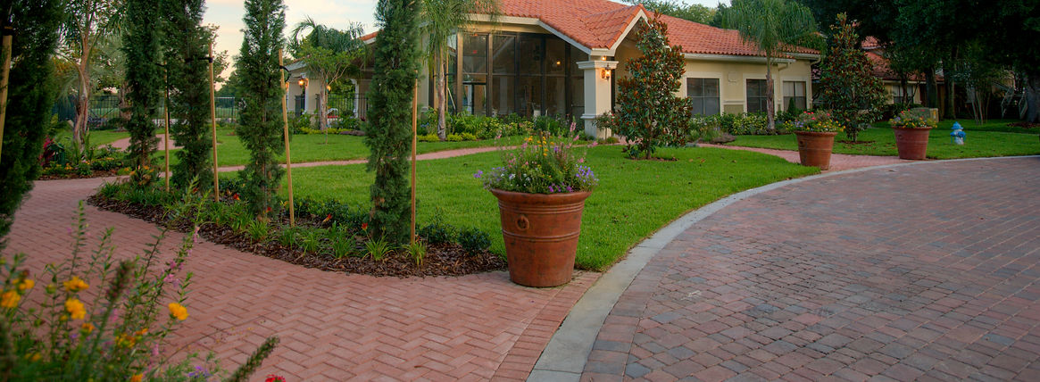 Large terracotta tiled villa surrounded by manicured lawns block paved pathways