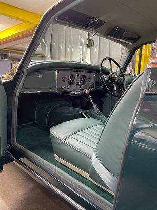 Classic car interior with green leather seats, vintage dashboard