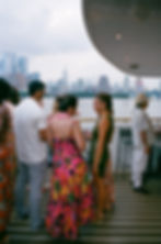 medium format film photo of a birthday party on a yacht in chelsea piers, nyc with view of manhattan skyline. bespoke tropical themed cruise boat luxury birthday party