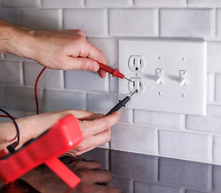 Electrician testing electrical outlet with multimeter.jpg