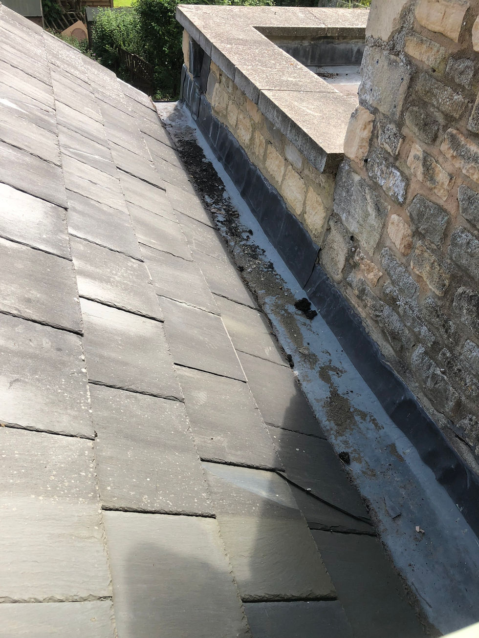 Lead valley roof repairs with slate tiles and Cotswold stone detailing.
