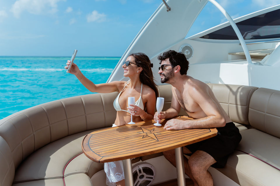 Just-married couple enjoying a yacht photoshoot on the turquoise waters of Aruba, taking a selfie with champagne aboard an Eden Luca Luxury Yacht Rentals in Aruba, photographed by Edrxck, Aruba photographer.