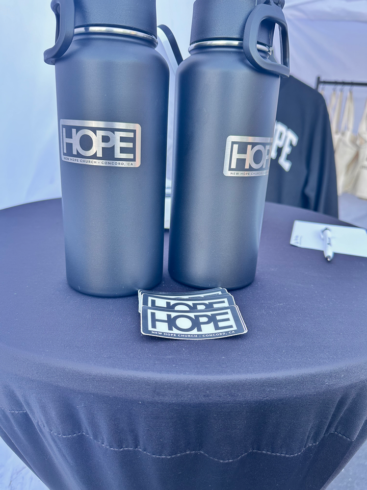 Two dark water bottles and sticker, all with 'HOPE'