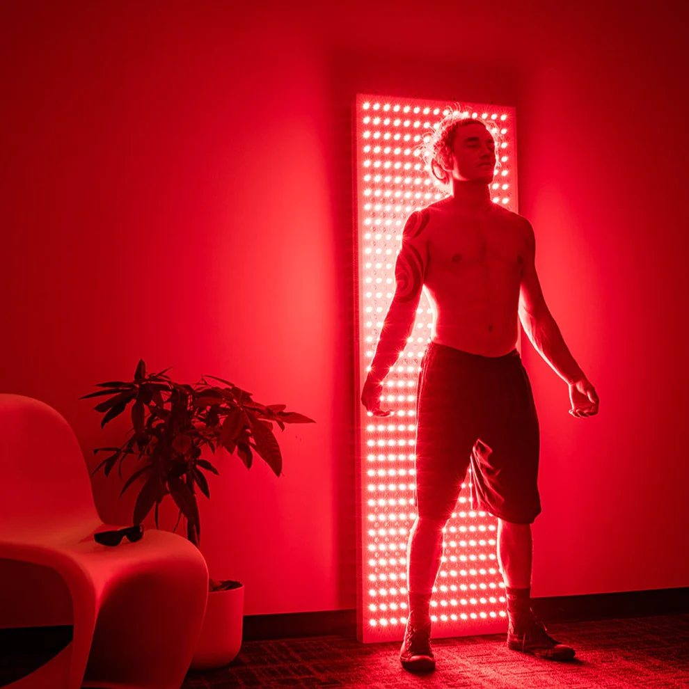 A man uses red light therapy on his back. 