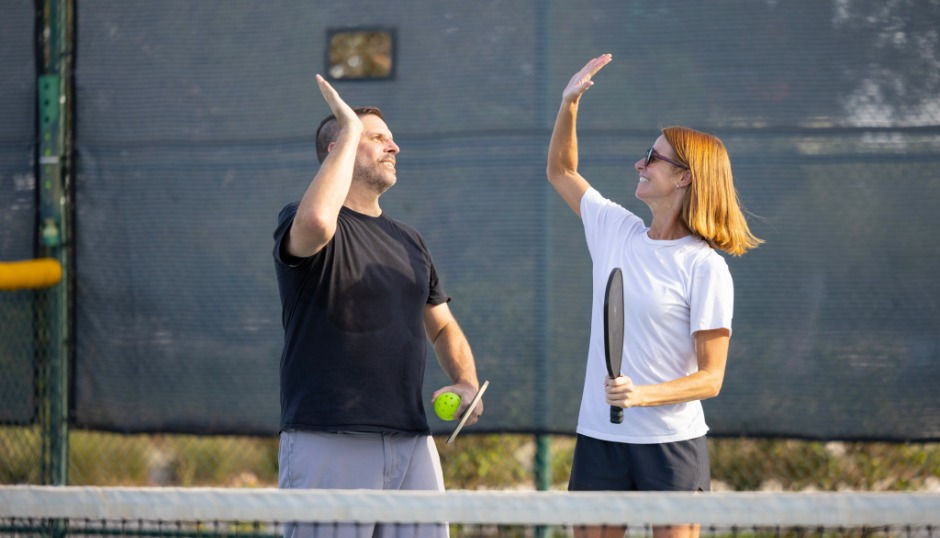 Pickleball doubles partners high fiving.