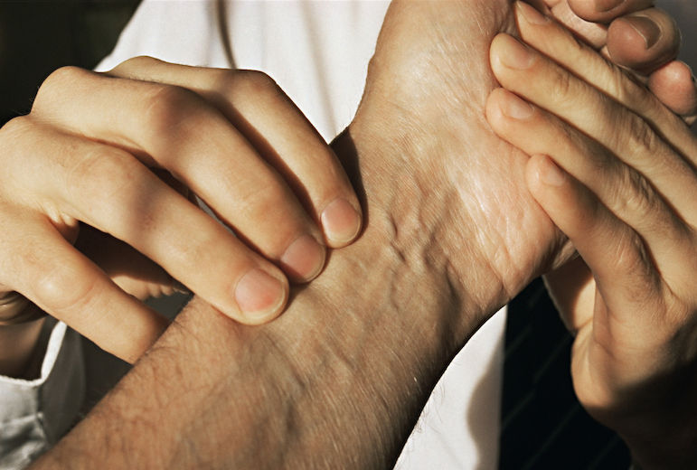 Calm Ayurvedic practitioner performing nadi pariksha (pulse diagnosis) on a patient in a serene clinical setting, representing personalized Ayurvedic consultation and dosha assessment.