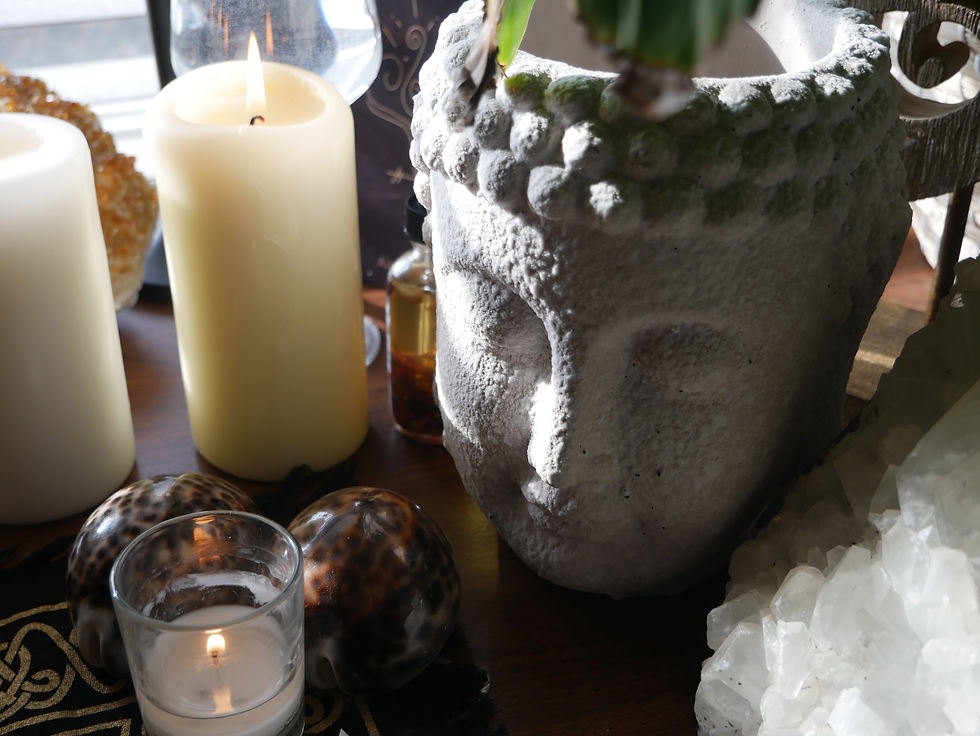 An empty Buddha pot on an altar sitting between a candle and crystal.