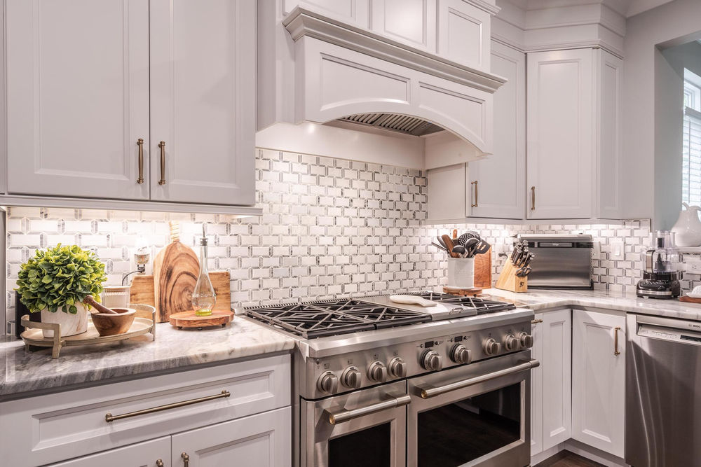 White kitchen cabinetry, a gas range and hexagonal tile backsplash in Oxford, Pennsylvania