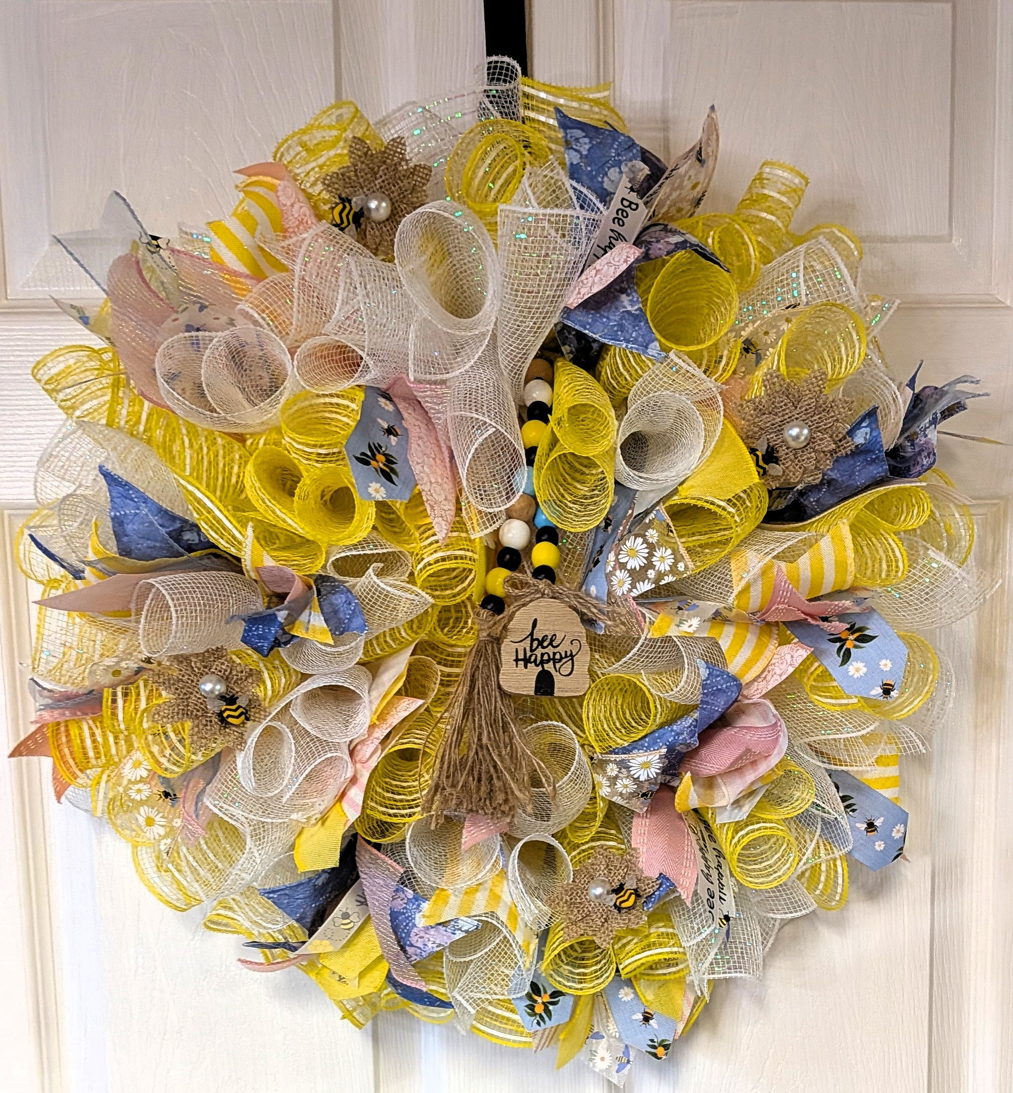 Soft pastel colored wreath with honey bee and bee happy embellishments.