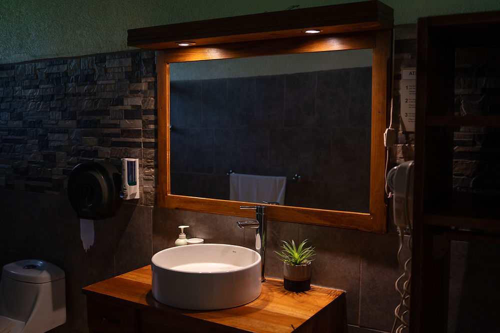 Tocador de baño moderno con espejo de madera y lavabo.