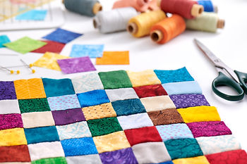 Tiny squares of fabric sewn together with thread, needles and scissors