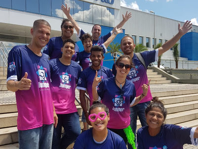 Grupo de funcionários da P&G sorrindo juntos para a foto em frente ao prédio.