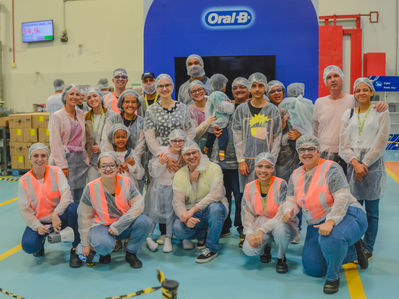 Grupo de pessoas na frente da marca Oral-B. EVENTOS CORPORATIVOS, sorrindo e posando.