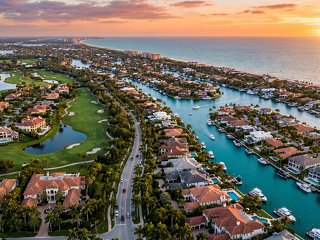Cinematic golden hour aerial view of an ultra-luxury coastal community in Southwest Florida. Features sprawling waterfront estates with private docks and yachts on a deep-water canal, bordering a pristine green golf course with luxury mansions. Palm-lined streets wind through the upscale neighborhood, leading toward a white sand beach and the open Gulf of Mexico under a sunset sky.
