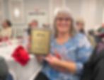 Jenny holding her Employee of the Year plaque and smiling at our Holiday Party.
