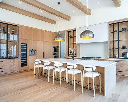 Large bright kitchen with sprawling island, oversized lighting above, oak cabinetry with black metal and glass cabinetry to display dishes.