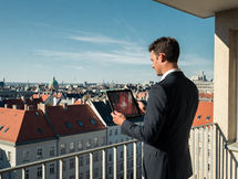 Immobilienentwickler analysiert mit einem Tablet KI-basierte Standort- und Grundstücksdaten mit Blick über eine europäische Stadt.