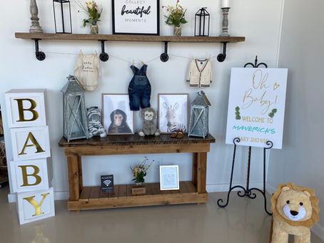 Welcome Guests display featuring a clothesline of baby clothes, large oversized blocks spelling BABY and stuffed lion and signage welcoming guest