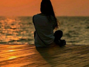 Frau, am Wasser sitzend und meditierend