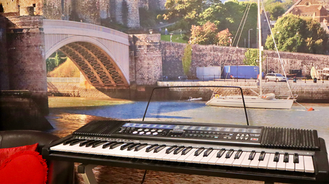 A keyboard with a wall painting in the background.