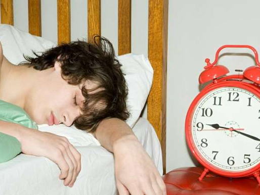 Teen boy sleeping with alarm clock