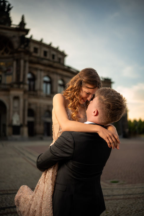 Hochzeitsfotograf Dresden: Intime Umarmung von hinten vor Semperoper, dunkler Stil.
