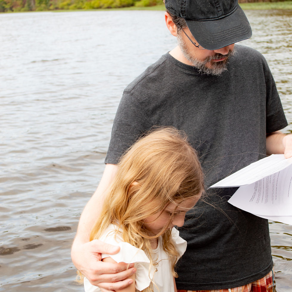 Man and girl standing in water praying before a baptism
