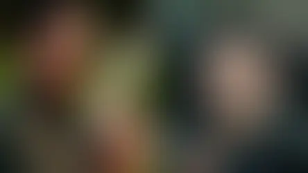 İki adam karşı karşıya. Soldaki çizgili takım elbise ve güneş gözlüğü takıyor, silah tutuyor. Sağdaki adama silahlar doğrultulmuş. Gergin atmosfer.