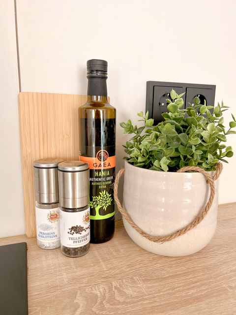 Olivenölflasche und Topf mit frischen Kräutern auf der Küchenarbeitsplatte