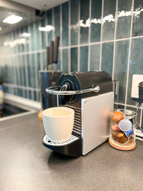 Moderne Kaffeemaschine mit Tasse auf der Arbeitsfläche.