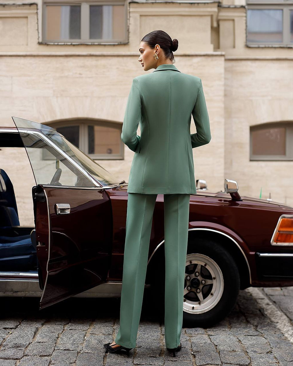 Thumbnail: Жінка в оливковому брючному костюмі з жилетом біля автомобіля.