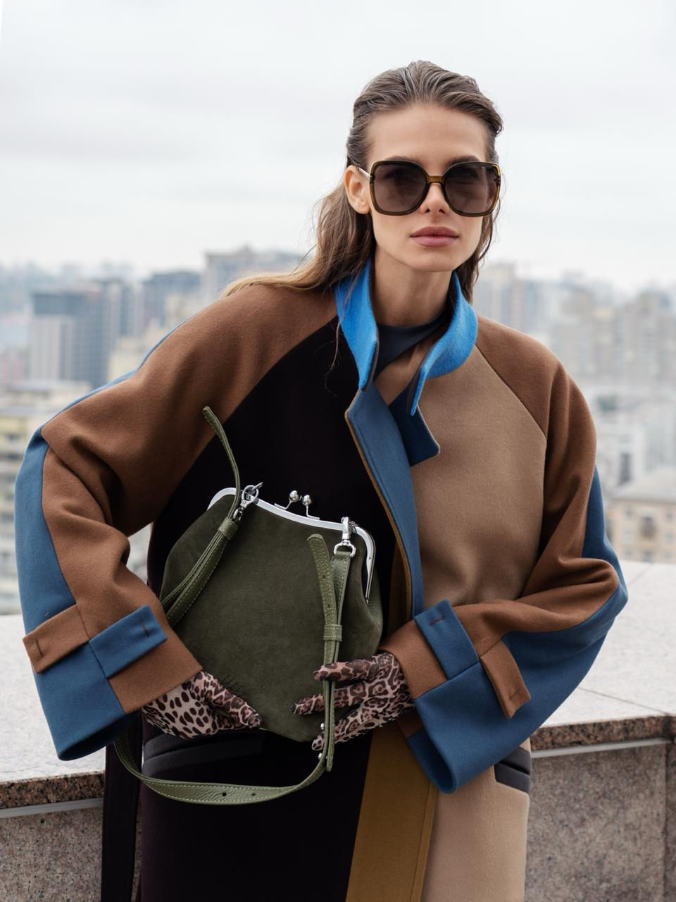 Жінка в пальті тримає сумку з натуральної замші хакі з металевою рамкою