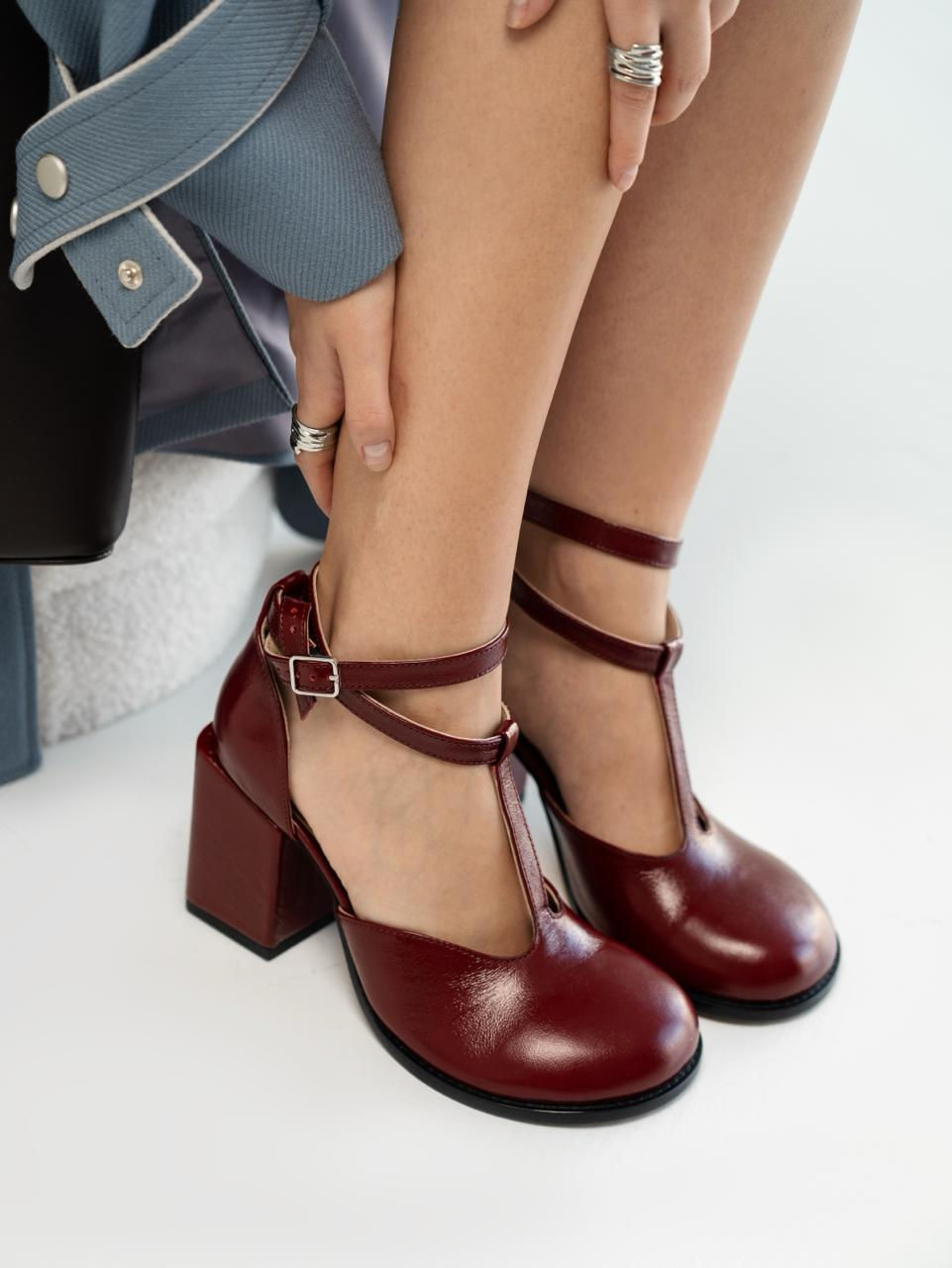 Zbliżenie na bordowe skórzane buty Mary Jane z potrójnym zapięciem na pasku.