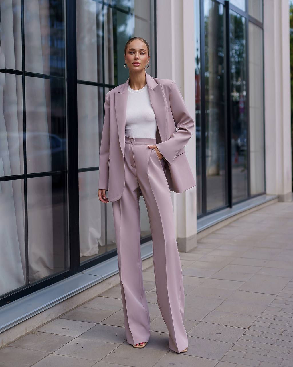 Жінка в елегантному пудровому брючному костюмі