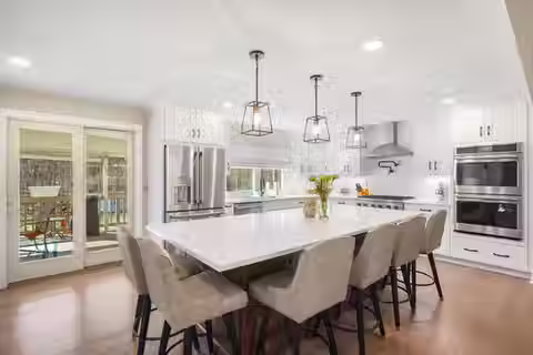 Luxury kitchen renovation by Peluso Construction featuring a large center island, custom white cabinetry, designer pendant lighting, premium appliances, and modern finishes in Rockland County NY.