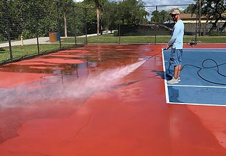worker pressure cleaning a tennis court