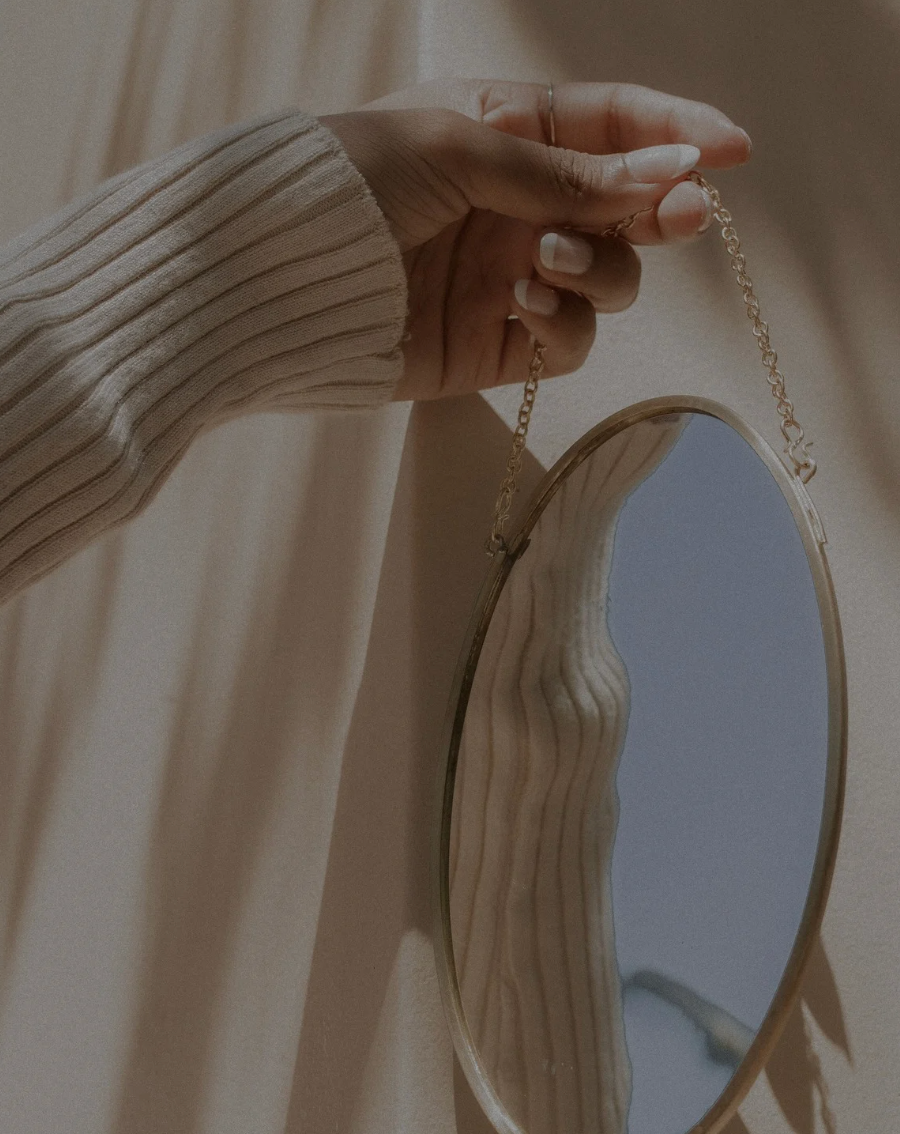 A woman holding a mirror to enhance her confidence factor