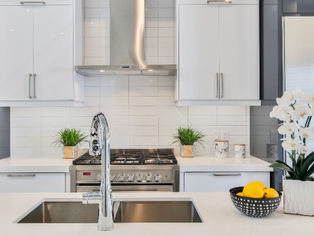 Modern kitchen with white cabinets and stainless steel appliances. Orchids and lemons on the counter add freshness and color.