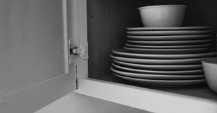 Close-up of a worn cabinet hinge needing adjustment, ideal for DIY repair and restoration projects.