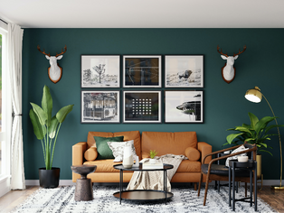 Living room with a sofa, green wall, and art gallery above. Plants, lamps, and a textured rug enhance the inviting setting.