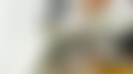 Person in gloves using a multimeter to test a wall socket in a room. Tools and electrical components scattered.