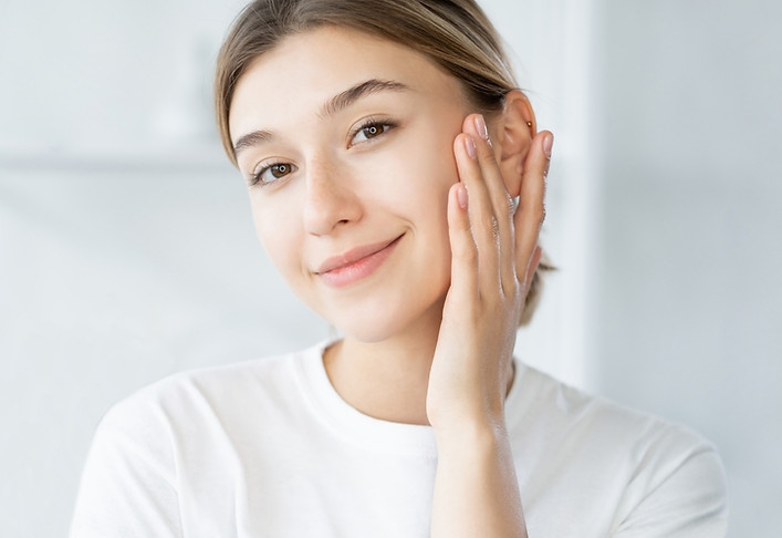 a woman smiling, touching her cheek for her beautiful face contour