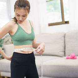 a woman measuring her waist line with a measuring tape