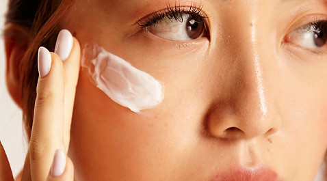 A woman putting cream on skin to combat acne