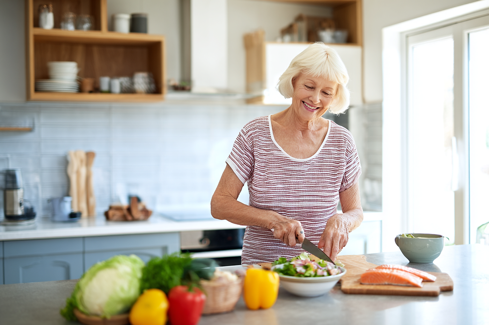 Femme âgée préparant un repas sain avec des légumes frais et du poisson dans sa cuisine.