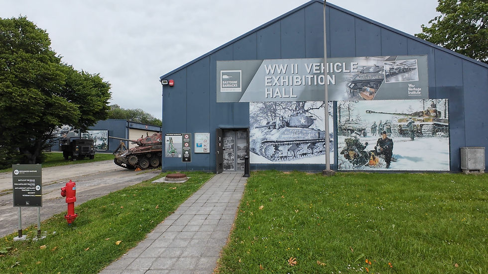 WWII Vehicle Exhibition Hall bei Bastogne Barracks, mit Panzern, Militärfahrzeugen, Schildern und grünem Vorplatz.