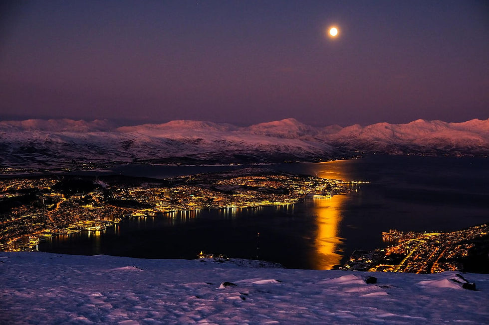 Nächtliche Schneelandschaft über Tromsø am Fjord, Vollmond spiegelt sich golden im Wasser, Berge im Hintergrund.
