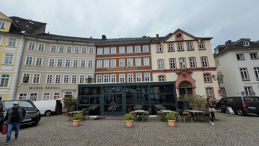 Historischer Platz mit pastellfarbenen Fassaden, Restaurant Wirt am Dom/Weinhaus Beppler, Passanten und grauem Himmel