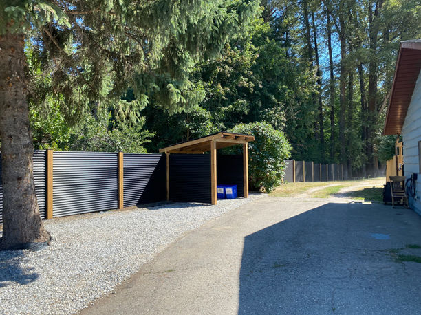 sleek black corrugated metal fencing separated by wooden posts creates privacy for a sicamous bc homeowner