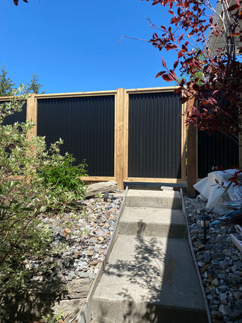 6 foot high corrugated black tin fence with thick wooden posts built by blue rhino fence in vernon